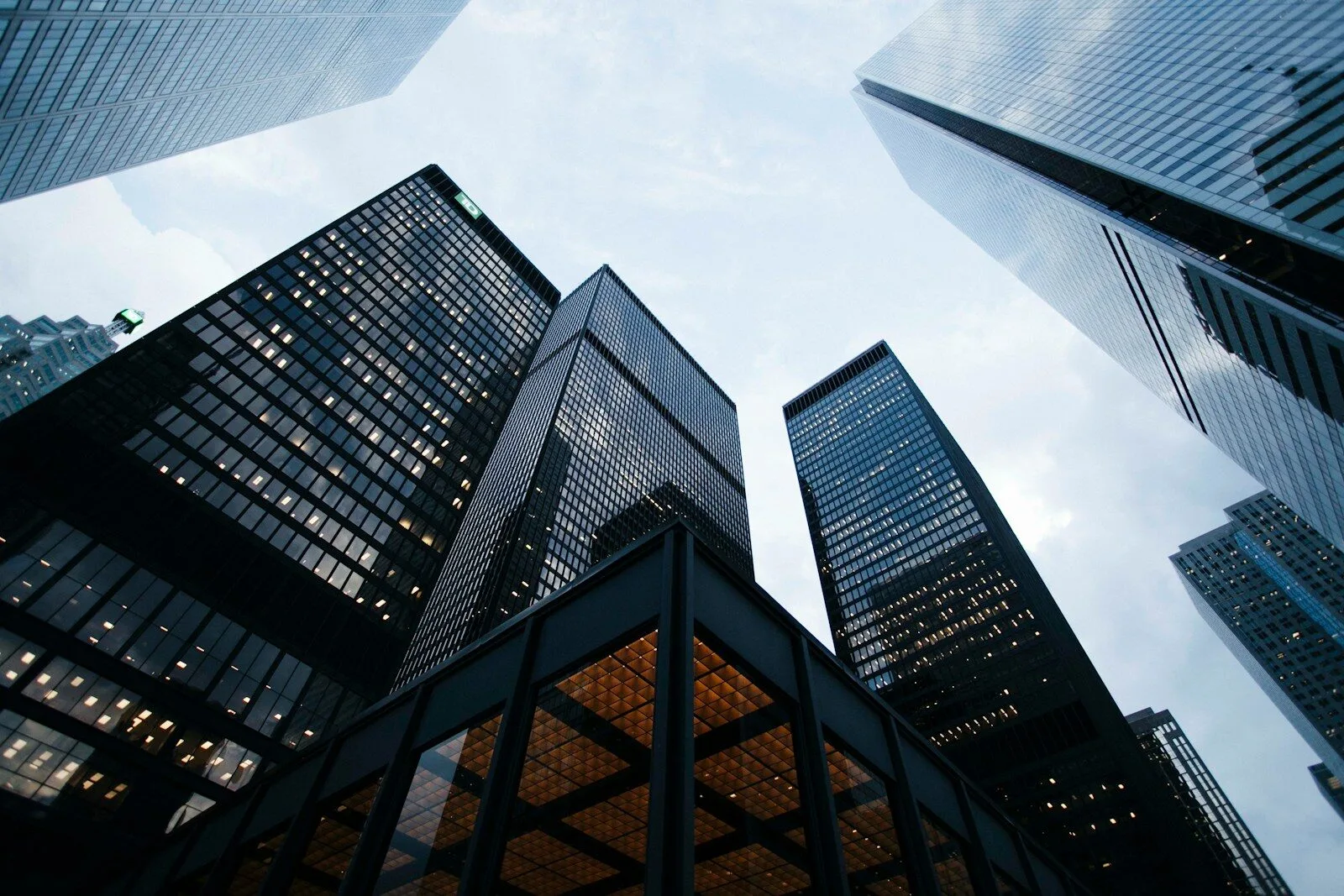 Perspective view of modern skyscraper facades with glass reflections of clouds and sky.